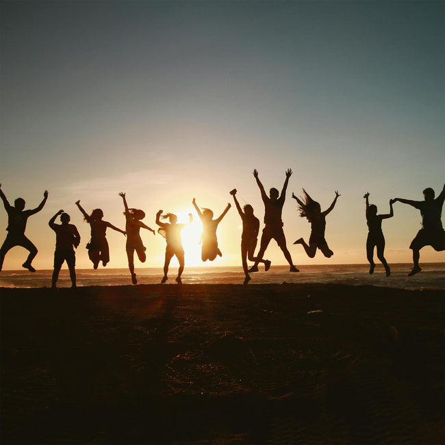 Silhouette of a group of people jumping against a sunset
