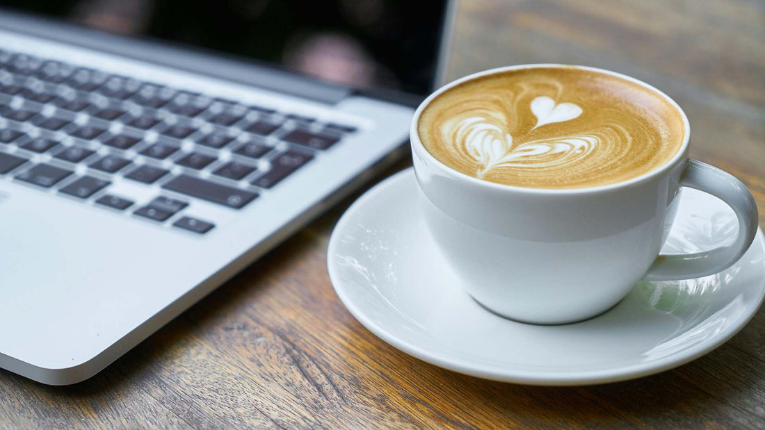 Cup of coffee with latte art next to laptop