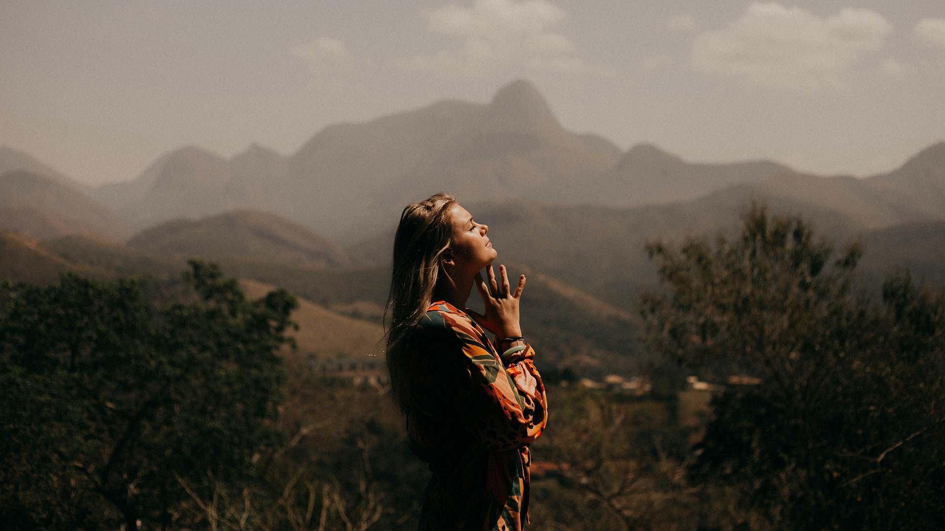 Side view of a woman with closed eyes, hands resting below her chin.