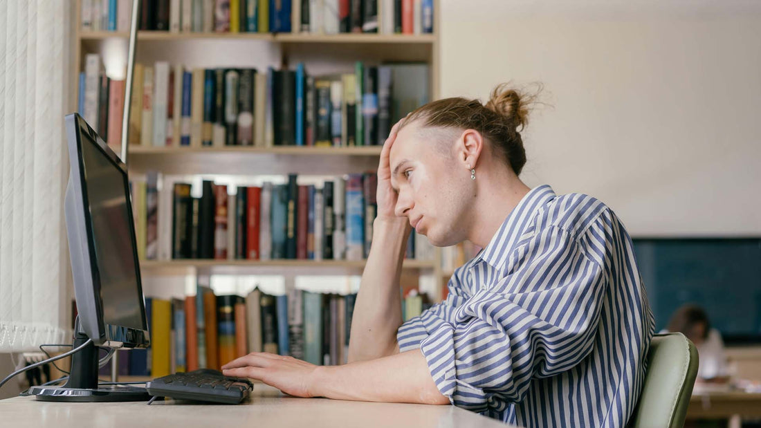 man studying while sitting in front of a computer in the library