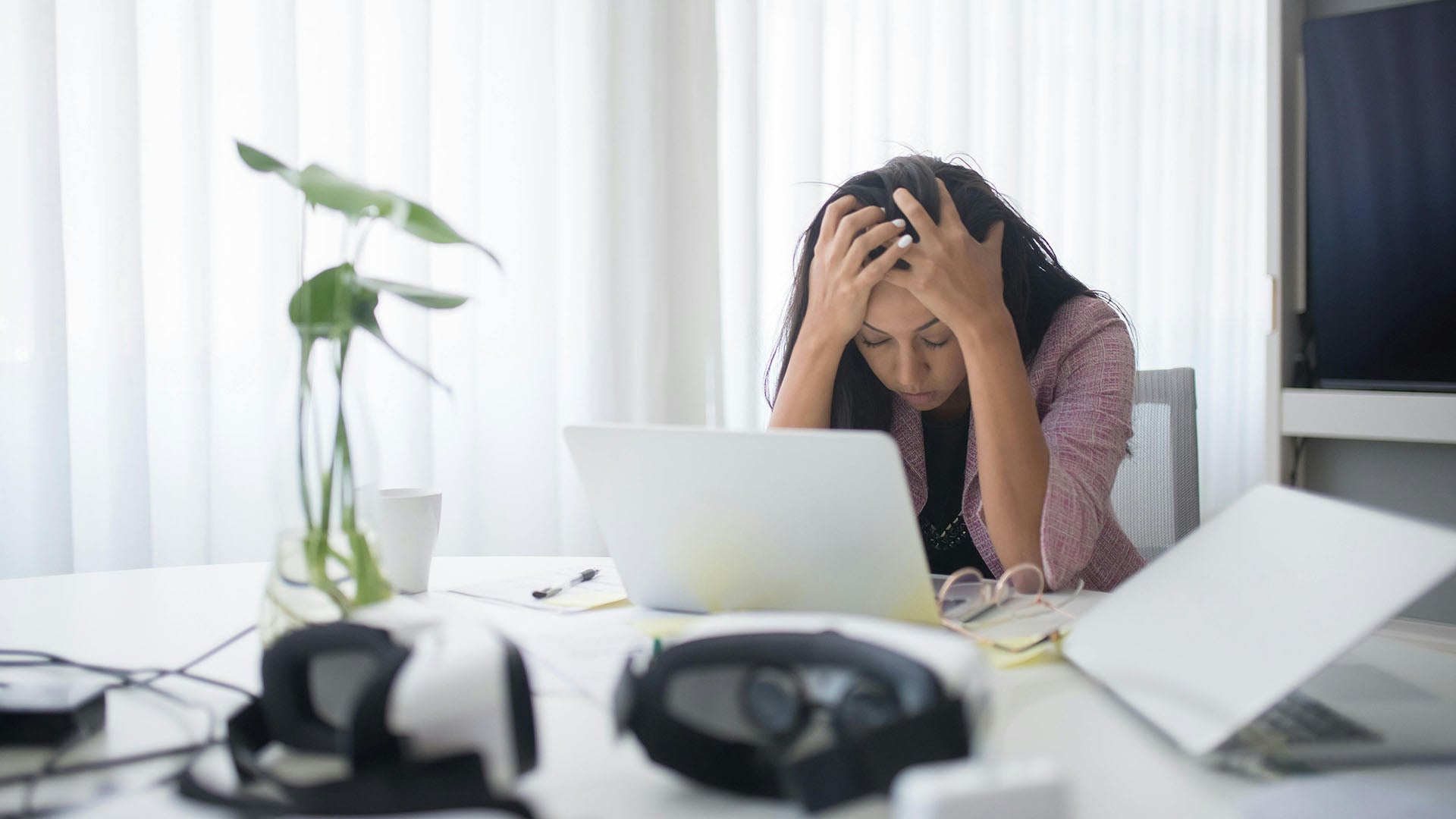 woman stressed out looking at laptop holding her head