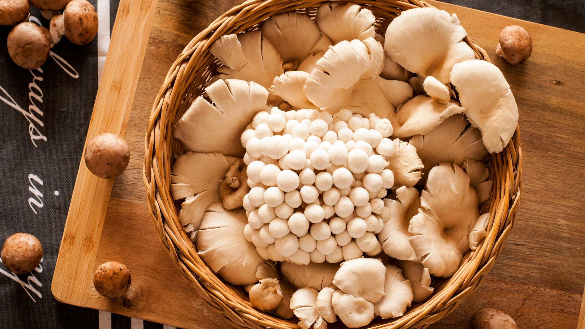 assorted mushrooms in a basket on a wooden board