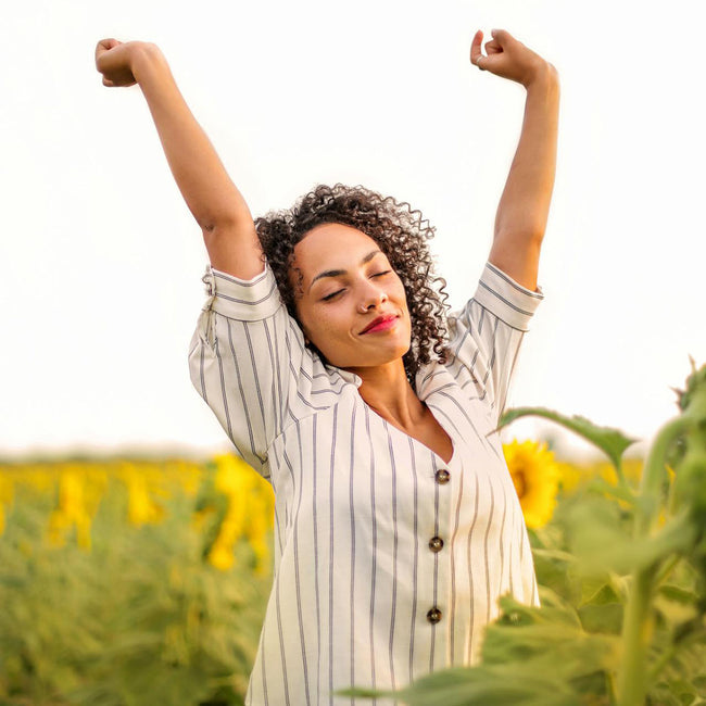 woman in a sunflower field and happily raising her arms