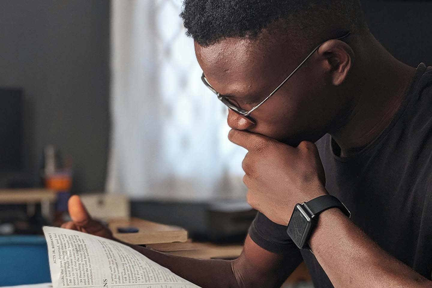 man sitting at desk reading a book