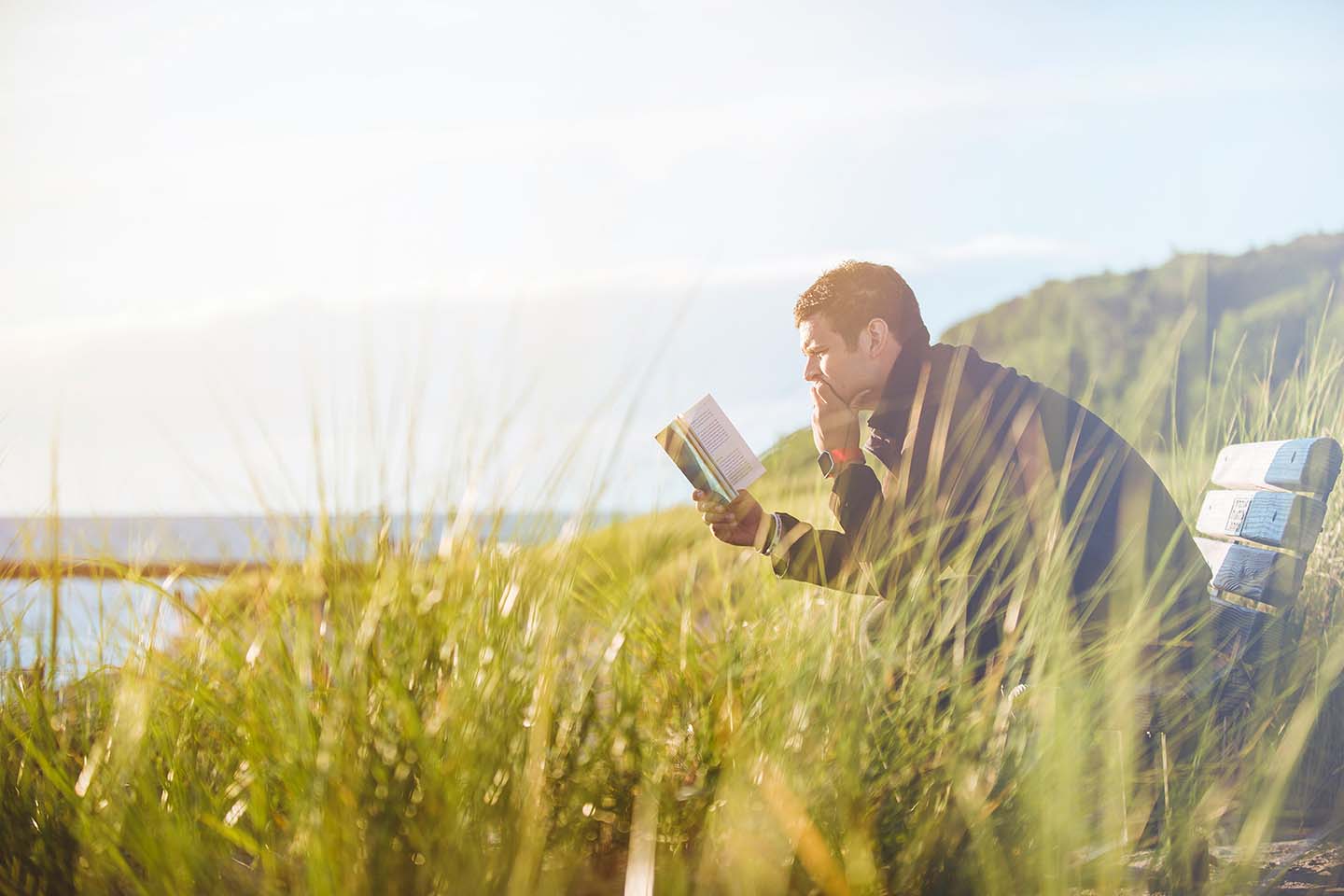 man sitting outside on a bench reading a book