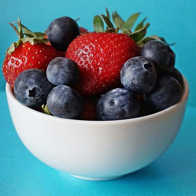 a white bowl full of blueberries and strawberries