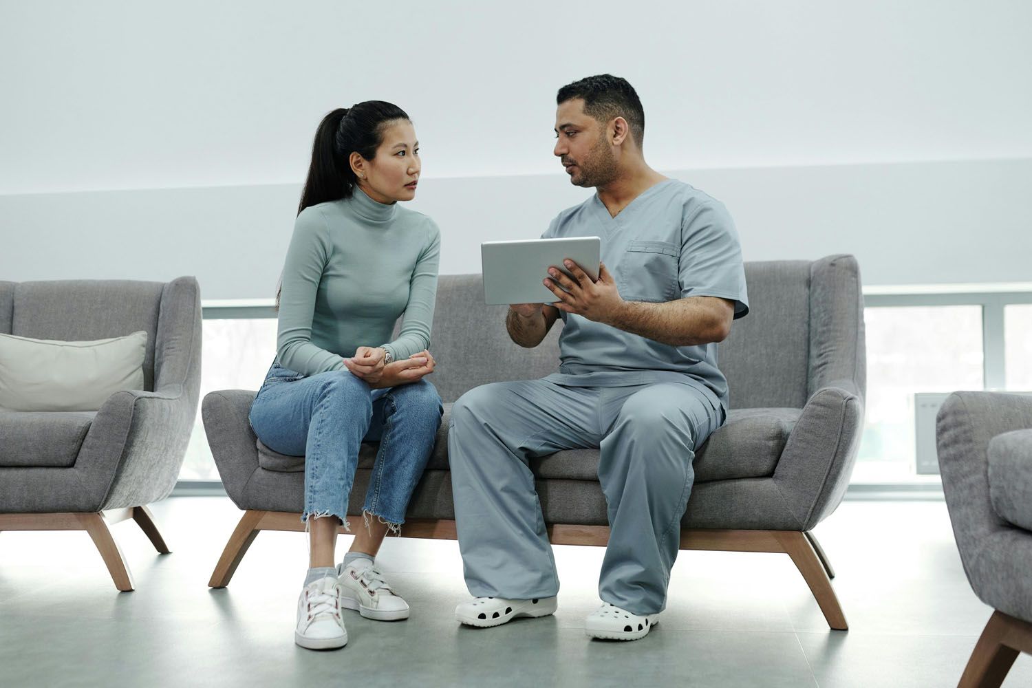 Doctor talking to a patient on a couch while holding a tablet