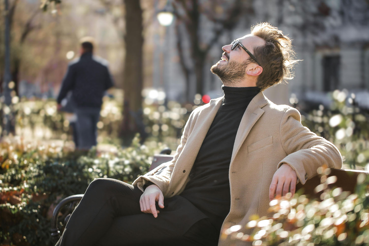 Man sitting on a bench smiling up at the sky